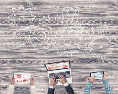 Ellerinde cihazlar bulunan üç kişilik bir grup iletişim ve ağ oluşturma sembolü olarak birlikte çalışıyor.