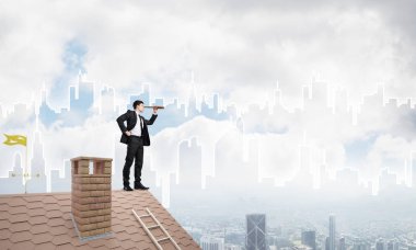 Çatıda takım elbiseli genç bir işadamı var. Karışık ortam