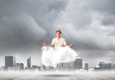 Adam beyaz giyim gözler tutmak kapalı ve seyir arka plan üzerinde cityscape manzaralı Cloud ahşap zemin üzerinde meditasyon sırasında konsantre.