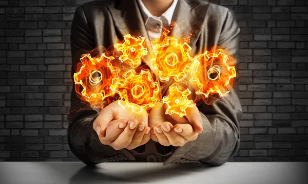 Businessman Suit Presenting Flaming Cogwheels Structure His Hands Dark Brick — Stock Photo, Image