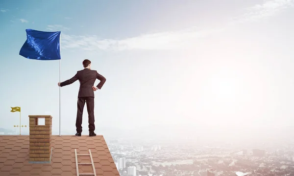 Businessman Standing House Roof Holding Blue Flag Mixed Media — Stock Photo, Image