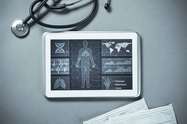 White tablet pc and doctor tools on gray surface