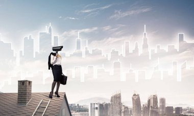 Evin çatısında baş durmak yerine kamerayla zum yapan yüzsüz iş kadını.