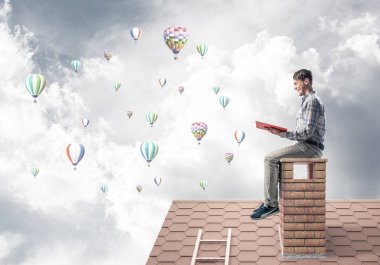 Elinde kırmızı kitap ile evin baca rahat oturan genç adam