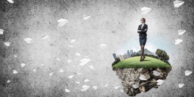 Yeşil yüzen adada beton zemine karşı duran kendine güvenen zarif bir iş kadını.