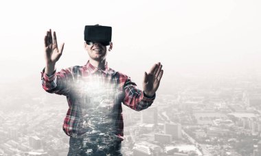 Sanal gerçeklik kulaklığı olan genç bir adam ya da şehrin arka planında 3 boyutlu gözlüklü.