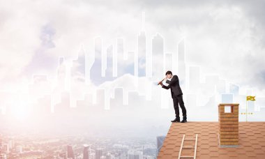 Çatıda takım elbiseli genç bir işadamı var. Karışık ortam