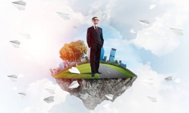 Mavi gök yeşil yüzen ada üzerinde duran zarif emin iş adamı