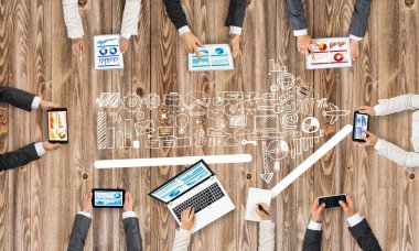 Ellerinde cihazlar bulunan bir grup insan, iletişim ve ağın sembolü olarak birlikte çalışıyor.