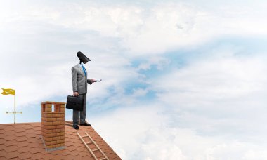 Evin çatısında baş durmak yerine kamerayla zum yapan yüzü olmayan bir iş adamı.