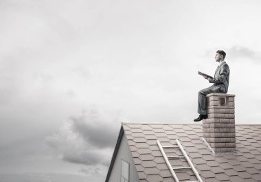 Elinde kırmızı kitap ile ev oturan takım elbiseli genç işadamı