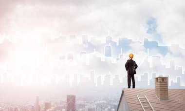 Takım elbiseli genç işadamı ve çatıda kask var. Karışık ortam