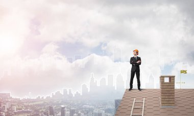 Takım elbiseli genç işadamı ve çatıda kask var. Karışık ortam