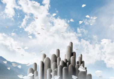 Açık havada, arka planda güzel manzarası olan uçan kağıt uçaklar arasında yer alan yüksek ve büyük taş sütunların resmi. Duvar kağıdı, telif alanı olan arkaplan.
