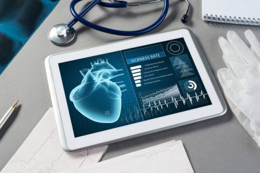 Gri yüzeyde beyaz tablet ve doktor araçları