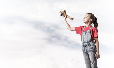 Elinde retro uçak modeliyle tulumlu şirin bir kız çocuğu.