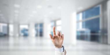 İş kadınının eli ekranda kapalı, arka planda parmak ve ofis var.