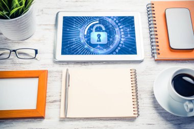 Ofis eşyalarıyla iş yeri ve ekranda asma kilit simgeleri olan tablet