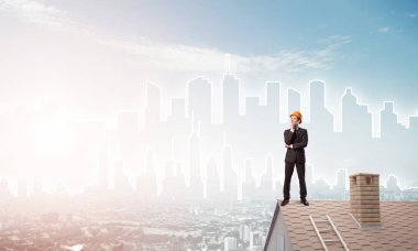 Takım elbiseli genç işadamı ve çatıda kask var. Karışık ortam