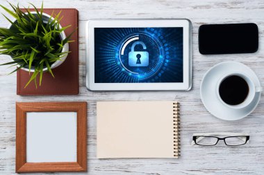 Ofis eşyalarıyla iş yeri ve ekranda asma kilit simgeleri olan tablet
