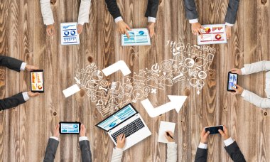 Ellerinde cihazlar bulunan bir grup insan, iletişim ve ağın sembolü olarak birlikte çalışıyor.