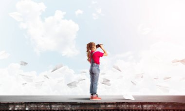 Dürbünle bakan, okul çağındaki sevimli kız çatıyı inşa ediyor.