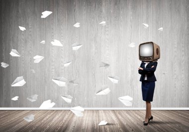 Kağıt uçaklar ile gri karanlık duvar boş oda içinde arka planda uçan arasında duran iş kadını kıyafetli kafa silah tutmak yerine eski Tv ile geçti.