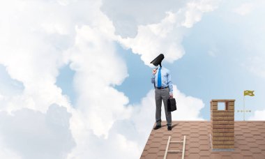 Evin çatısında baş durmak yerine kamerayla zum yapan yüzü olmayan bir iş adamı.