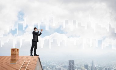 Çatıda takım elbiseli genç bir işadamı var. Karışık ortam