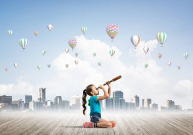 Ahşap zeminde oturan tatlı kız ve havada uçuşan hava yastıkları.