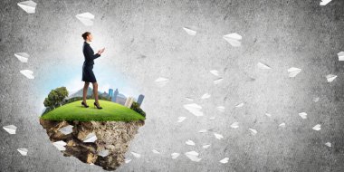 Yeşil yüzen adada beton zemine karşı duran kendine güvenen zarif bir iş kadını.