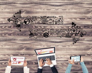 Ellerinde cihazlar bulunan bir grup insan, iletişim ve ağın sembolü olarak birlikte çalışıyor.