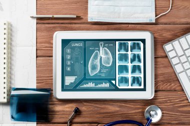 Beyaz tablet bilgisayar ve doktor aletleri ahşap masada.