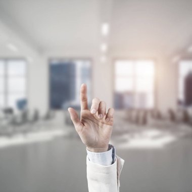 İş kadınının eli ekranda kapalı, arka planda parmak ve ofis var.