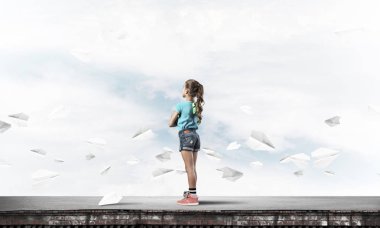 Sevimli kız etrafında uçan çatı ve kağıt uçaklar binasında ayakta