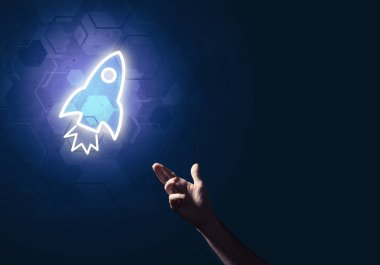 Koyu arkaplanda parlayan roket simgesi ve insan eli