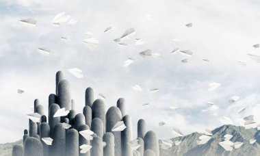 Açık havada, arka planda güzel manzarası olan uçan kağıt uçaklar arasında yer alan yüksek ve büyük taş sütunların resmi. Duvar kağıdı, telif alanı olan arkaplan.