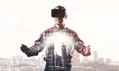 Sanal gerçeklik kulaklığı olan genç bir adam ya da şehrin arka planında 3 boyutlu gözlüklü.