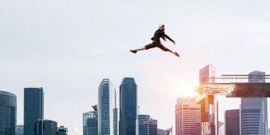 İş kadını zorlukların üstesinden sembolü olarak büyük boşluğu beton köprü üstünden atlayarak. Cityscape zemin üzerine güneş ışığı ile. 3D render.