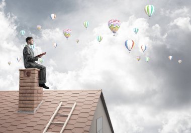 Elinde kırmızı kitap ile ev oturan genç işadamı