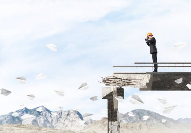 Genç takım elbiseli mühendis ve dürbün ile gökyüzü arka plan üzerinde kırık köprüde kağıt uçak uçan arasında duran seyir kask. 3D render.