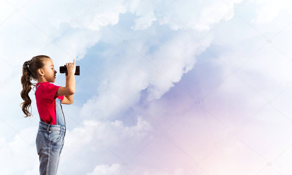 Little cute girl in overalls against sky background dreaming about future