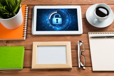 Ofis eşyalarıyla iş yeri ve ekranda asma kilit simgeleri olan tablet