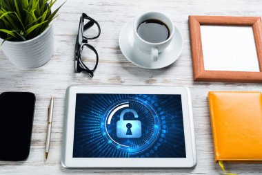 Ofis eşyalarıyla iş yeri ve ekranda asma kilit simgeleri olan tablet