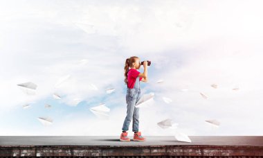 Dürbünle bakan, okul çağındaki sevimli kız çatıyı inşa ediyor.