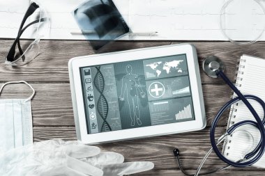 Beyaz tablet bilgisayar ve doktor aletleri ahşap masada.