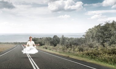 Genç adam gözleri koruma kapalı ve seyir ile güzel ve nefes kesici manzara arka plan üzerinde bulut yukarıda yolun üzerinde meditasyon sırasında konsantre.