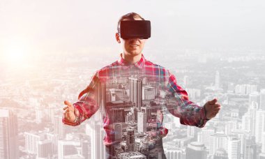 Sanal gerçeklik kulaklığı olan genç bir adam ya da şehrin arka planında 3 boyutlu gözlüklü.