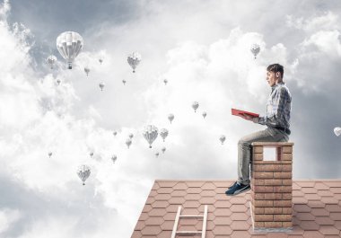 Elinde kırmızı kitap ile evin baca rahat oturan genç adam