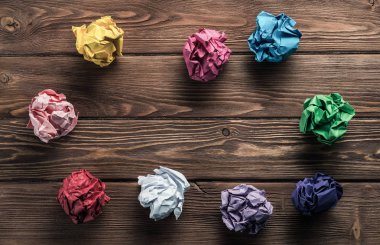 Birden çok renkli crampled kağıt topu kümesi üzerinde ahşap masa yeni fikirlerden arama aracı olarak yerleştirilir..